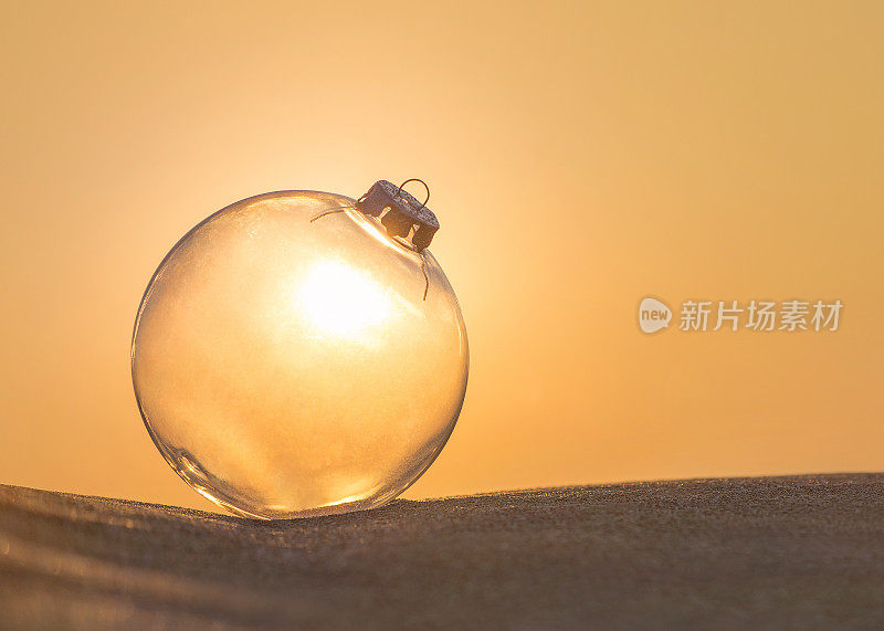 圣诞树装饰透明玻璃球在日落海滩