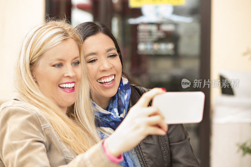 女性朋友在户外咖啡馆用智能手机自拍。