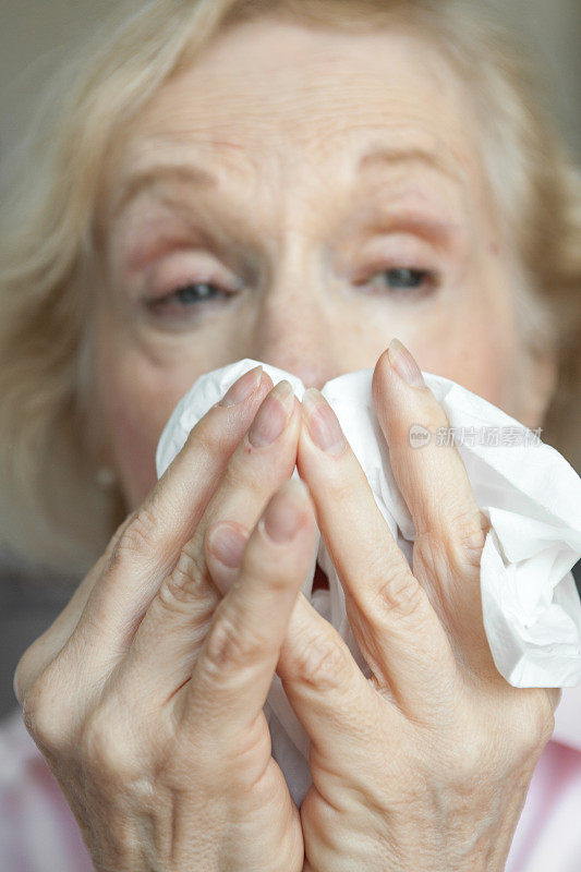 老妇人用纸巾擤鼻子