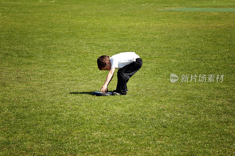 五岁男孩在操场上捡飞盘