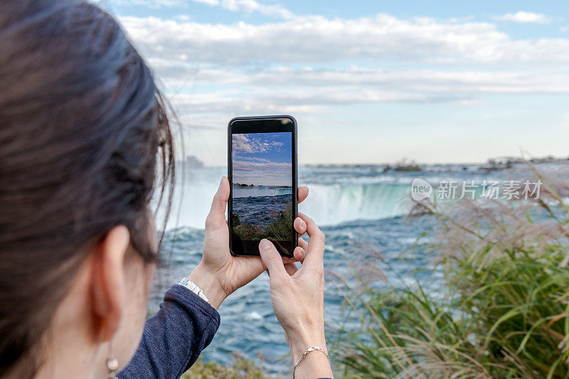 一名女子在尼亚加拉大瀑布用智能手机拍照
