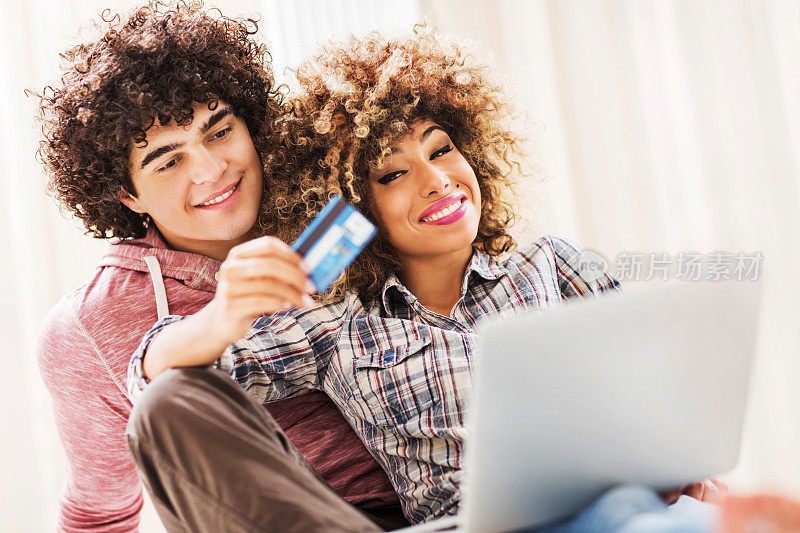 年轻的一对微笑着一起享受网上购物。