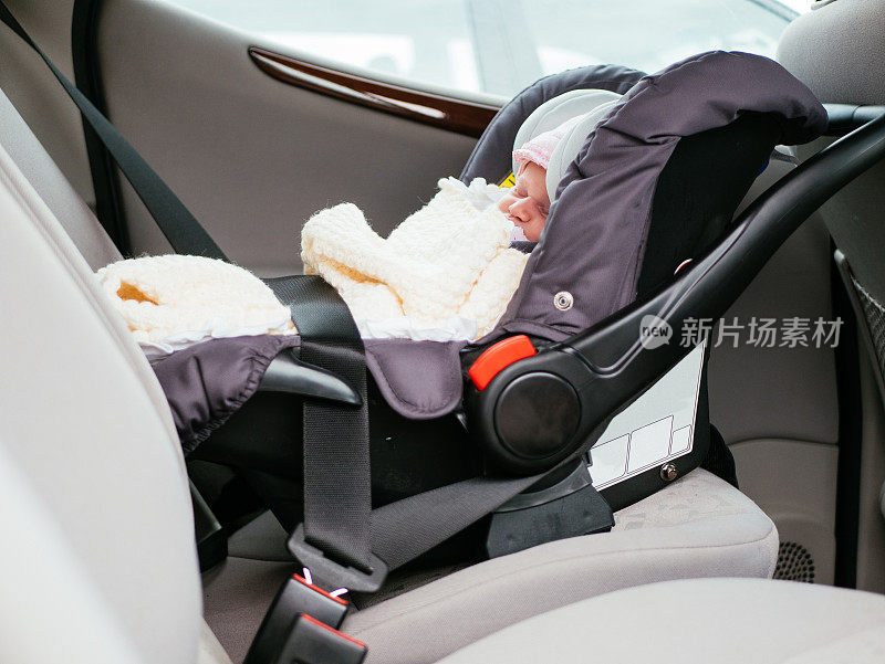 可爱的两周大的婴儿睡在汽车后座的汽车座椅上