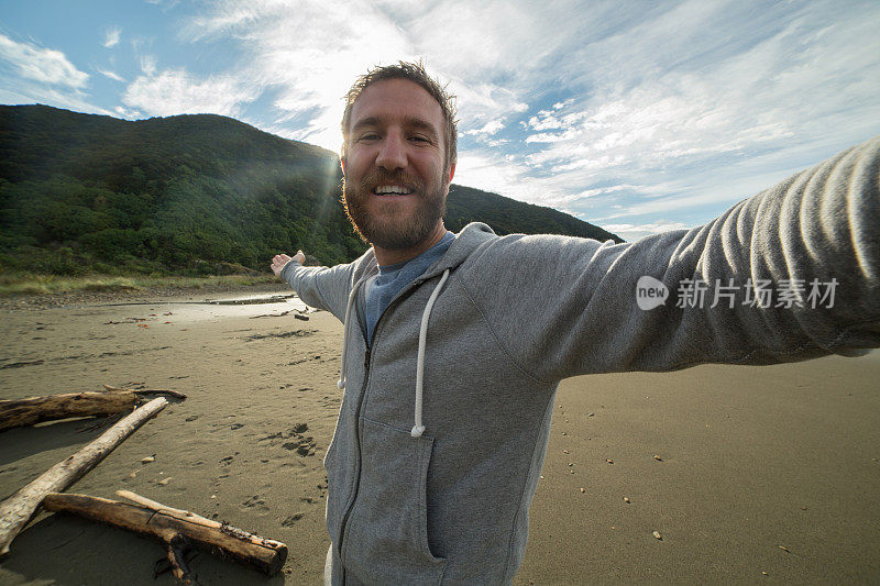 一个快乐的年轻人在狂野的海滩上自拍