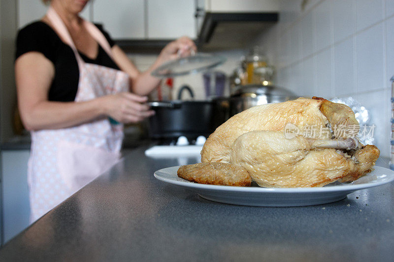 家庭主妇在厨房准备食物烤鸡的前景