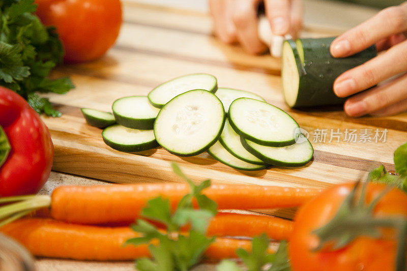 女人在家庭厨房里切黄瓜，蔬菜。