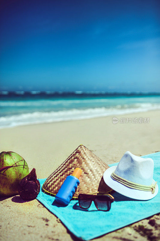 翻盖太阳镜毛巾帽太阳保护乳液和椰子在海滩附近的海洋