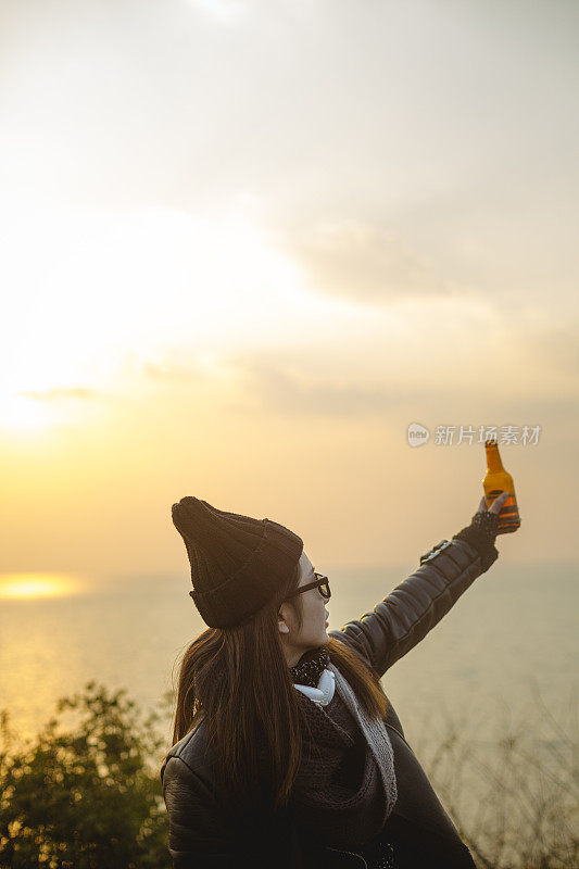 夕阳西下，年轻女子喝着啤酒