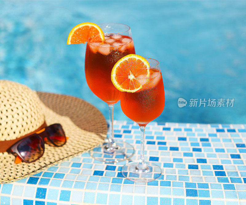 玻璃杯的橙色酒精鸡尾酒在蓝绿色的水背景