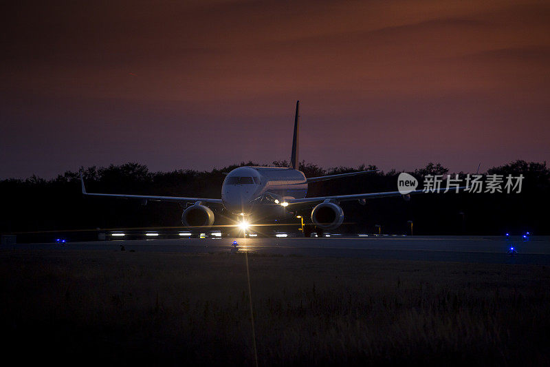 夕阳西下时在跑道上滑行的飞机被照亮