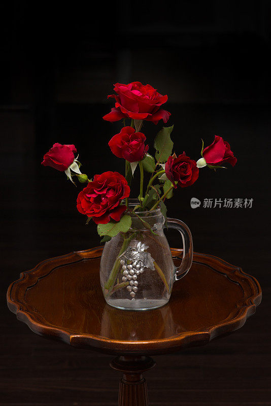 红玫瑰，唐璜，插在古董花瓶里，背景是黑色的