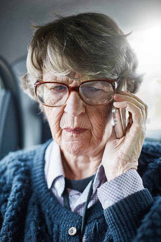 年长的女乘客用手机看起来很担心