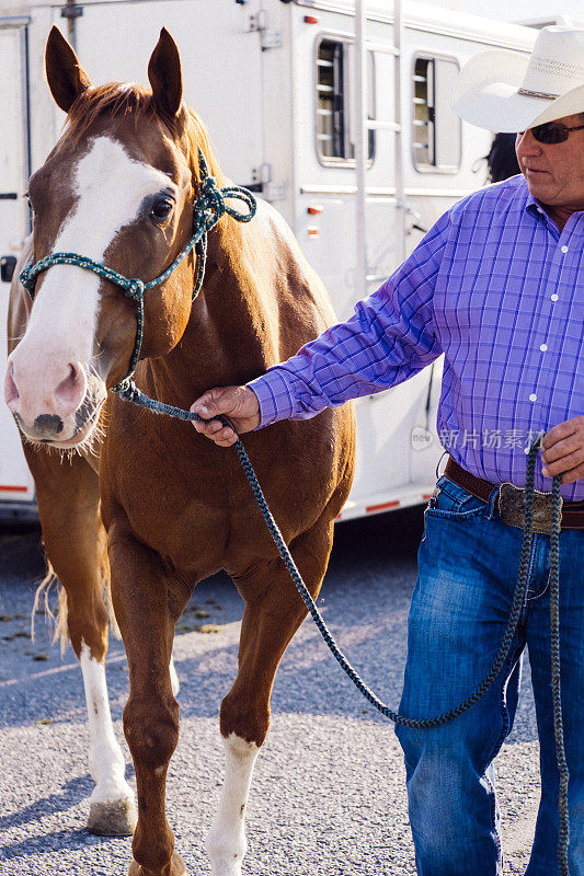 中年牛仔，牵着他的马离开拖车后面