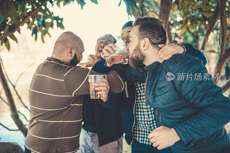 一群朋友微笑着在公园野餐时祝酒喝酒