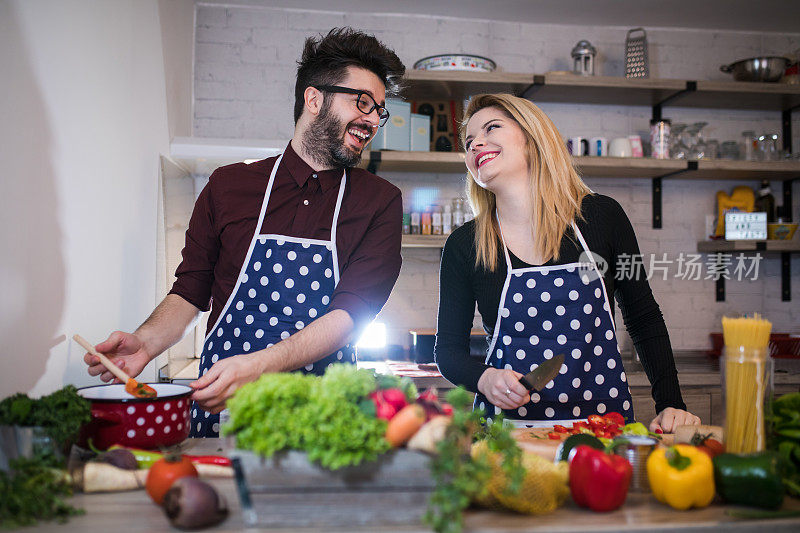 微笑的年轻夫妇在厨房做饭