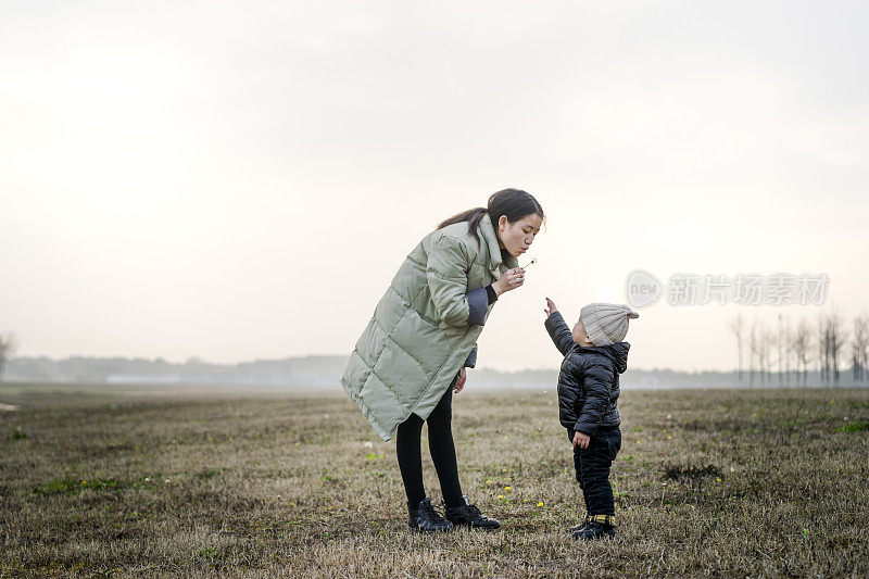 年轻的母亲和婴儿儿子一起在草地上玩