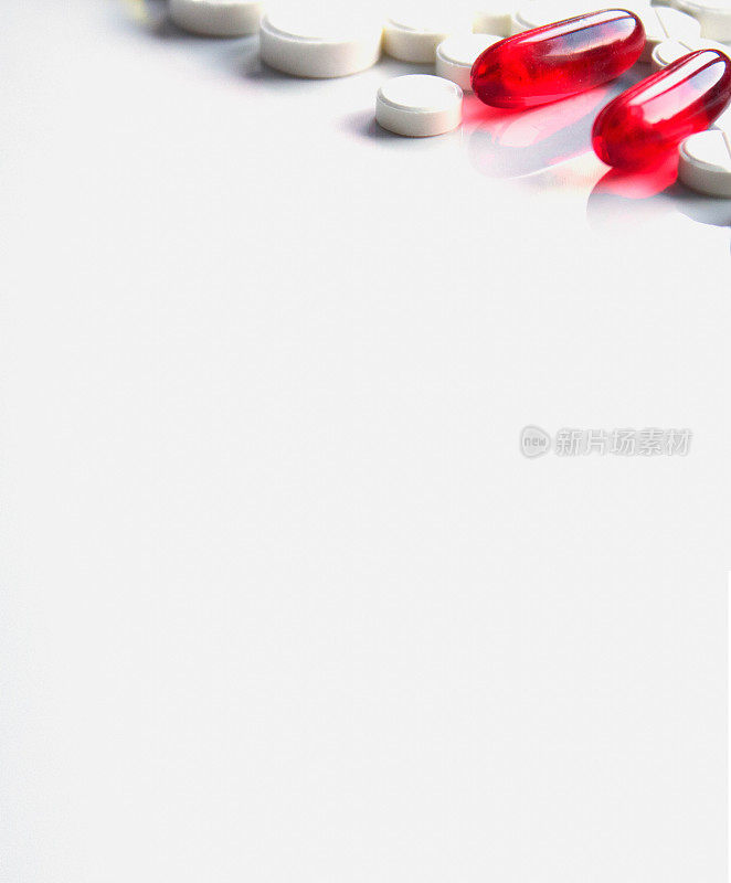 红色软胶囊和药丸，白色垂直背景，复制空间