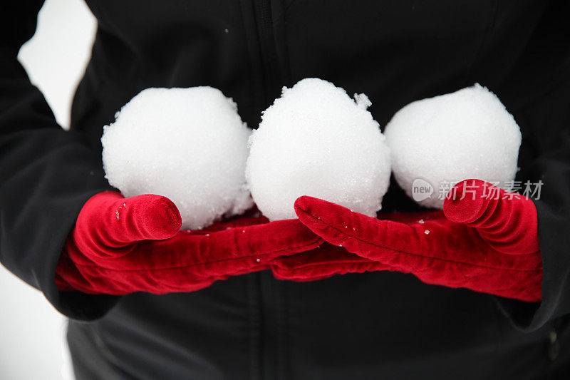 红色魅力天鹅绒手套拿着三个打雪仗雪球