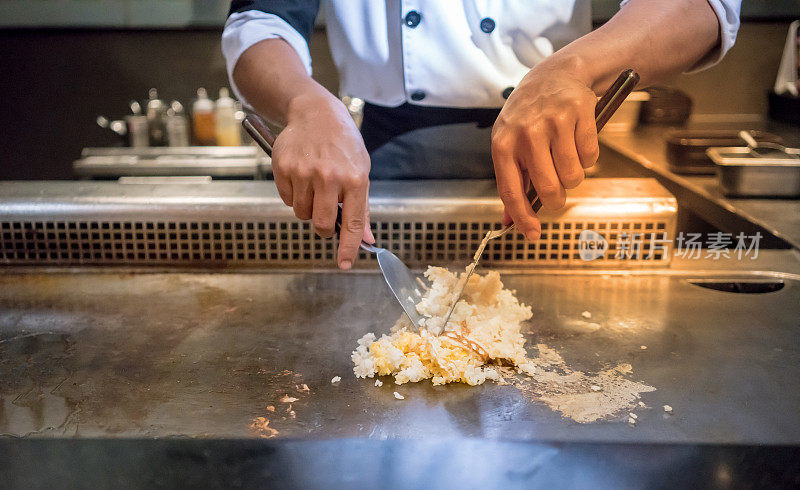 厨师的手在顾客面前用热锅煮大蒜炒饭。日本Tepanyaki牛排