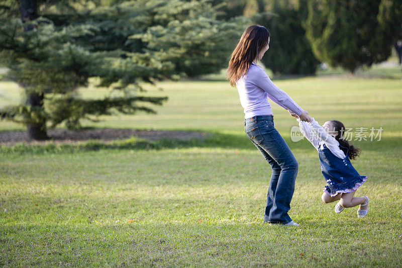女儿被妈妈拉起来在草地上玩耍