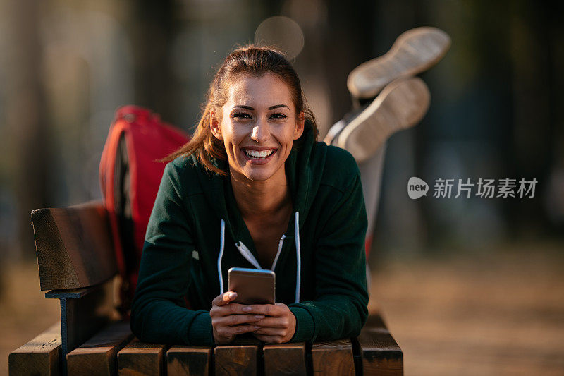 漂亮的年轻运动女性与智能手机在户外