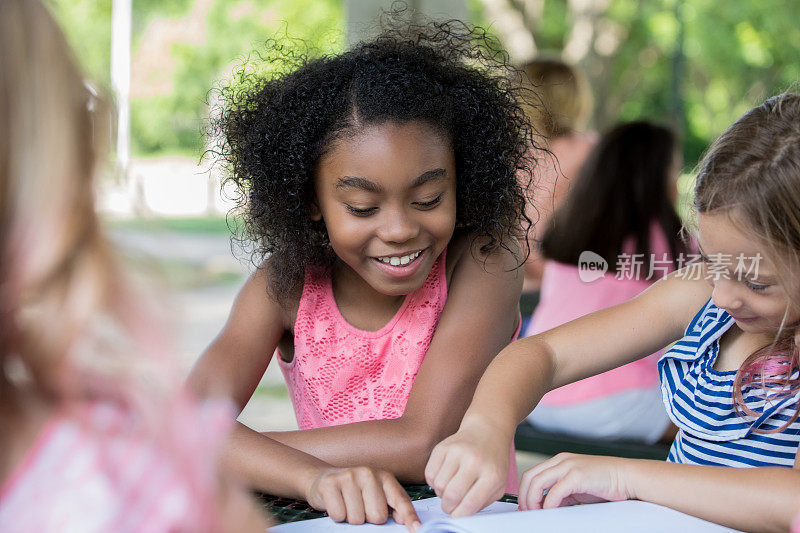 可爱的非洲裔美国小学女孩与一群朋友一起完成学校作业