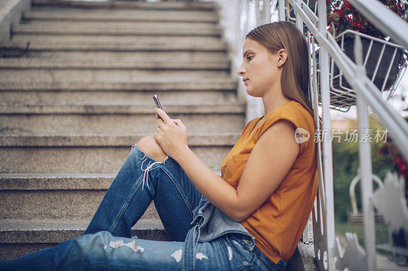 年轻女孩坐在楼梯上发短信