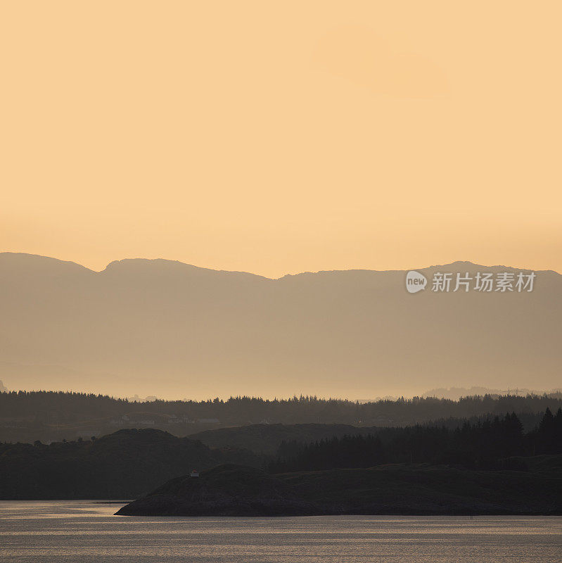 美丽宁静的挪威风景沐浴在一个平静的温暖发光的橙色黎明日出。山景逐渐退到背景中。有足够的空间来放置副本。