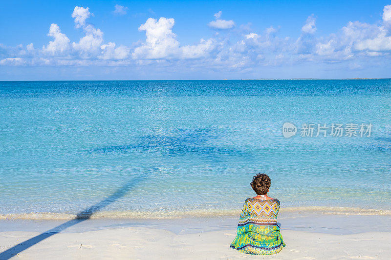 特克斯和凯科斯群岛，普罗维登夏莱斯——坐在萨波迪拉湾海滩上的女人