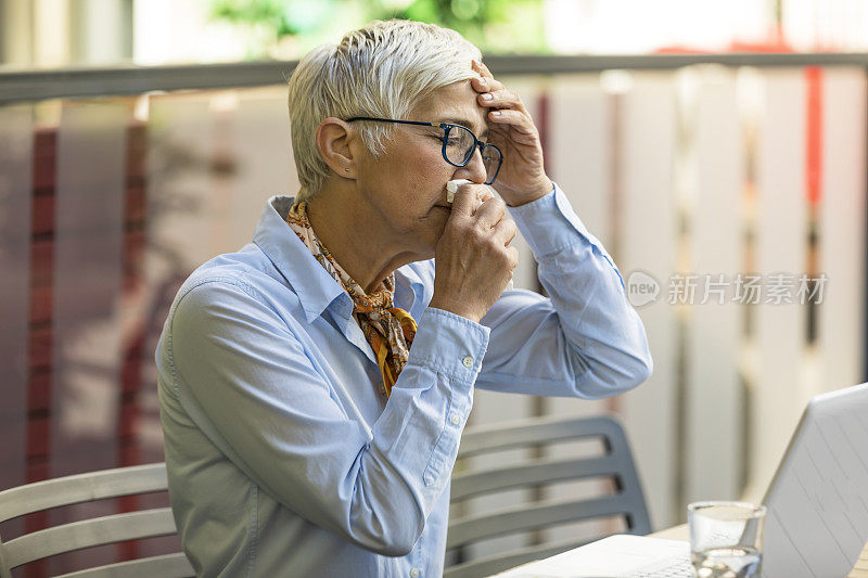 成熟的女商人坐在餐厅里感觉不舒服