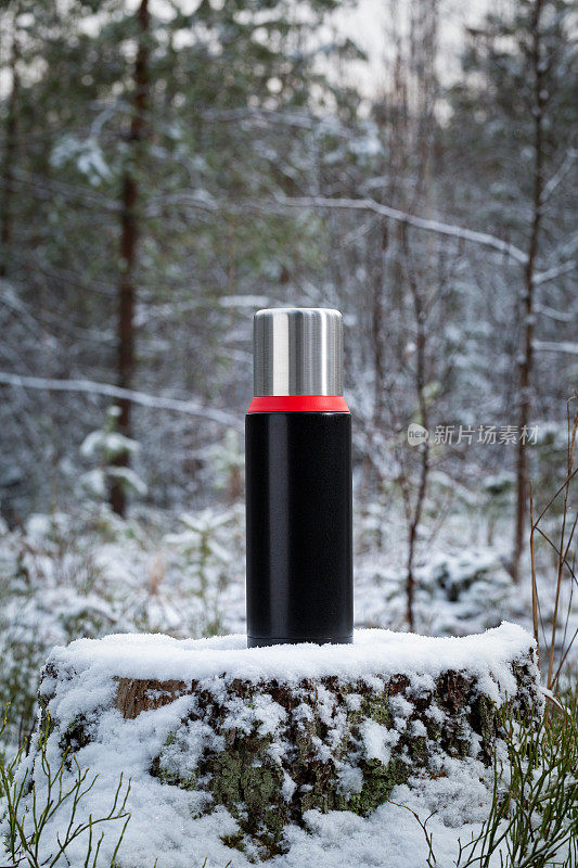 保温瓶放在森林里的一个老树桩上。