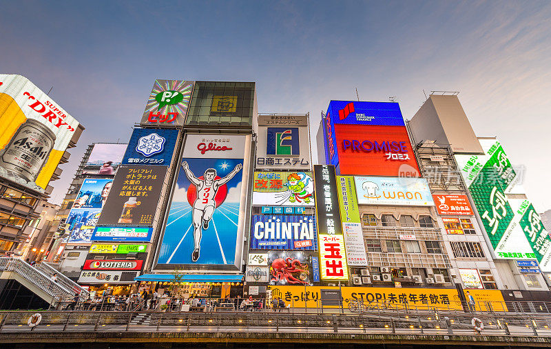 在日本大阪的道顿堀，五颜六色的广告牌照亮了大阪夜市周围的商店和零售店