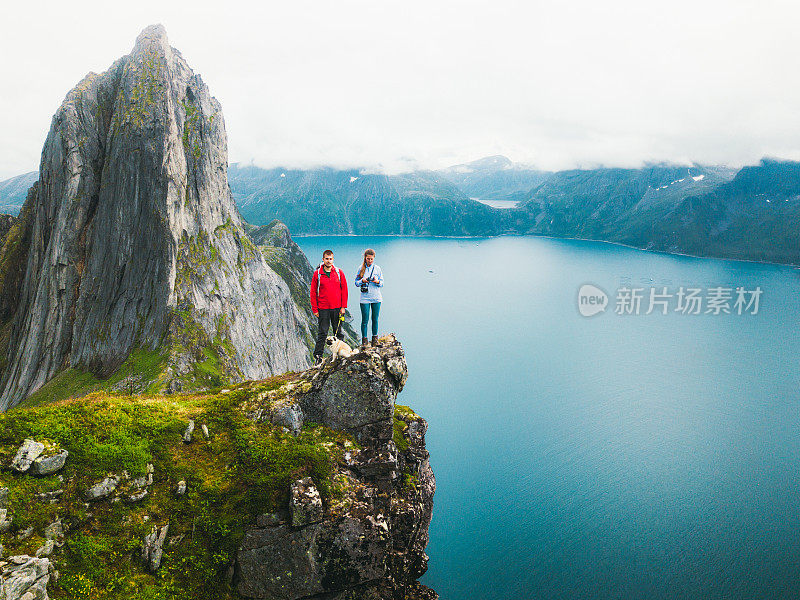 一对夫妇和狗高兴地在山顶上与峡湾的看法