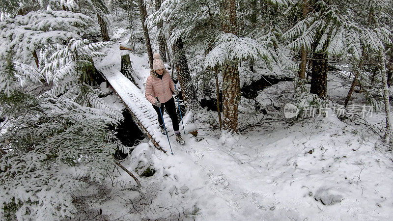 女性徒步旅行者走在被雪覆盖的木板路上