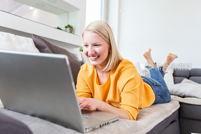 快乐的女孩在笔记本电脑上聊天。微笑的金发女人在电脑上给朋友发短信。社交媒体，交流和技术概念，复制空间墙上