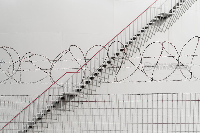 金属栅栏，铁丝网和盘旋在石油储存设施外部的楼梯