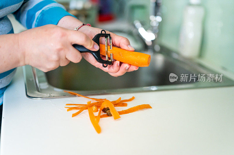 女性的手在厨房削胡萝卜的特写