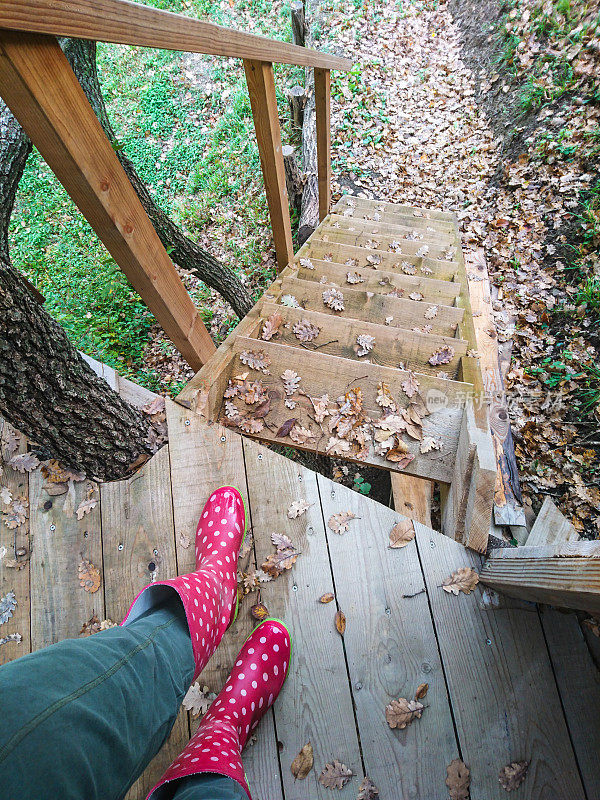穿着红色橡胶靴子的腿在户外木制楼梯上