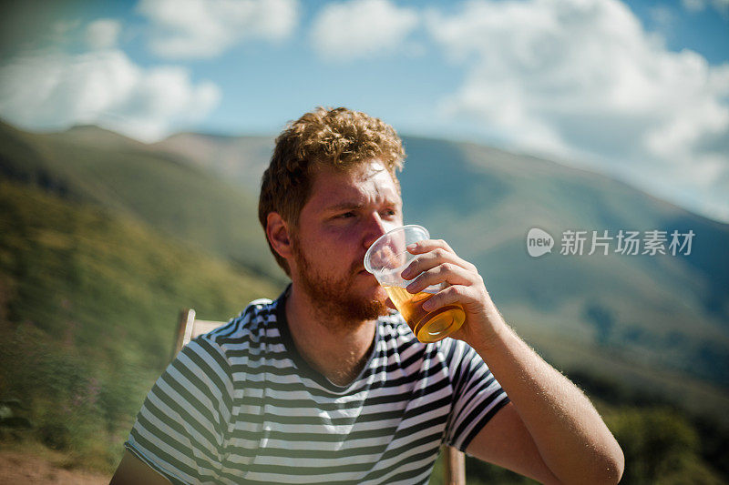 他正在山顶上喝着啤酒休息