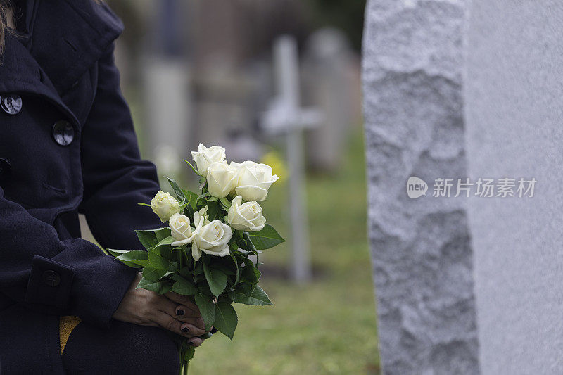 一个女人在坟墓前送花