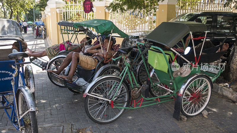 在金边，一些三轮车骑手在炎热的白天休息。