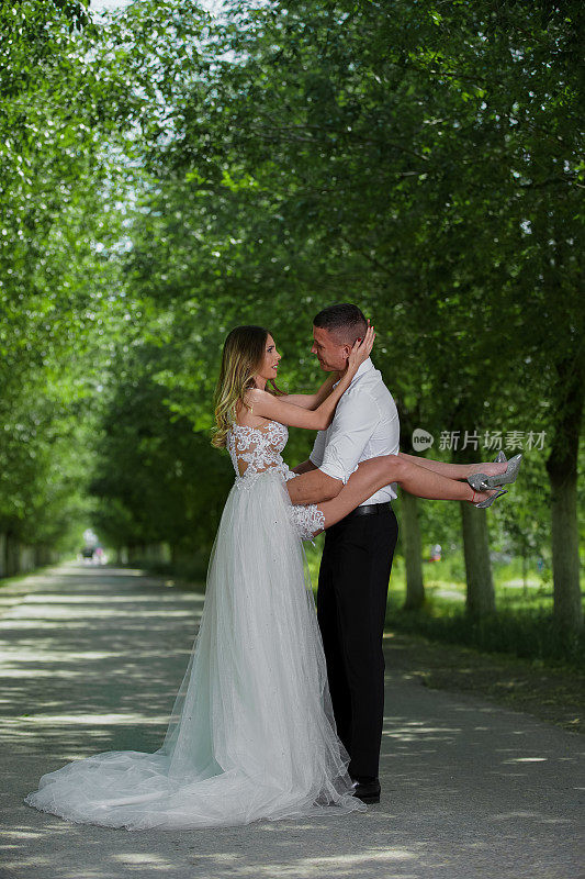 美丽的新婚夫妇在户外的汽车前面