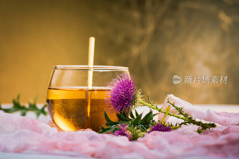 牛奶蓟草药茶和花孤立在金色的背景