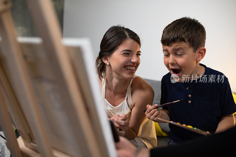 一个年轻的女人和一个可爱的男孩在一边画画一边笑