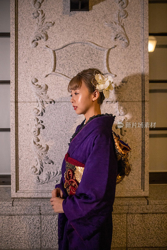 年轻女子的肖像在“Furisode”和服站在白色墙壁在晚上