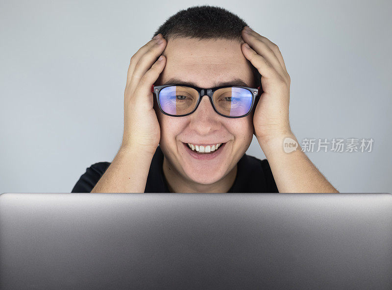 这个人看了看笔记本电脑，笑了，对他看到的东西感到惊讶。对你在互联网上看到的东西的情绪和反应的表达。震撼内容的概念。