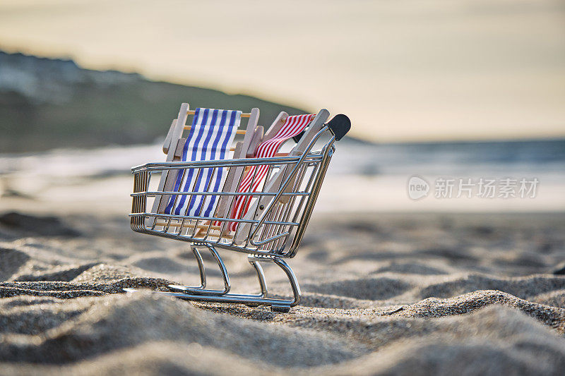 一个阳光明媚的秋天下午，康沃尔纽基菲斯特拉海滩的沙滩上有一个带两把躺椅的迷你购物推车，这是一个度假概念。