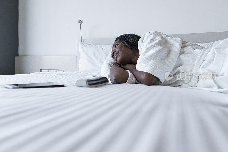 一个漂亮的黑人女人在辛苦工作一天后穿着睡袍躺在床上