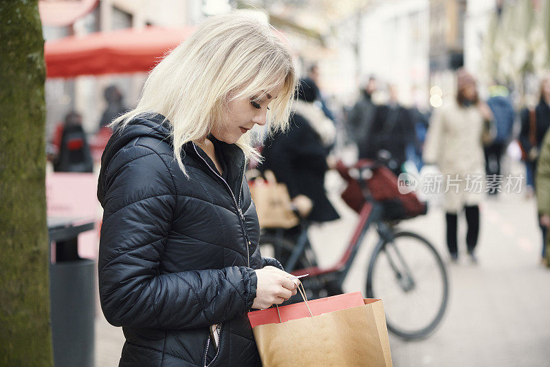 一个女人站在街上看纸条