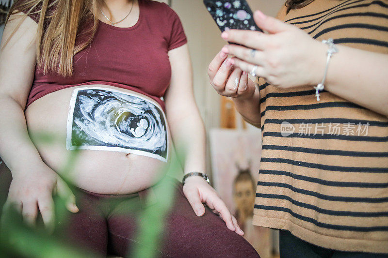孕妇露出肚子——她要生孩子了。未来的母亲。怀了个大肚子。在孕妇的肚子上画画-在孕妇的肚子上画画